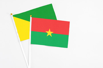 Burkina Faso and French Guiana stick flags on white background. High quality fabric, miniature national flag. Peaceful global concept.White floor for copy space.