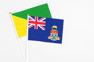 Cayman Islands and French Guiana stick flags on white background. High quality fabric, miniature national flag. Peaceful global concept.White floor for copy space.