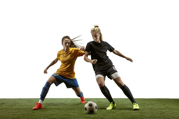 Young female soccer or football players with long hair in sportwear and boots training on white background. Concept of healthy lifestyle, professional sport, motion, movement. Fight for goal.