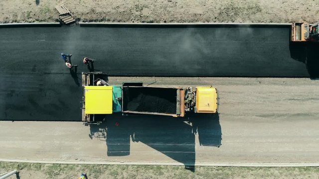Top view of an asphalt road being made. Asphalt paver machine on a road construction site.