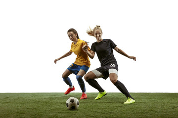 Obraz na płótnie Canvas Young female soccer or football players with long hair in sportwear and boots training on white background. Concept of healthy lifestyle, professional sport, motion, movement. Fight for goal.