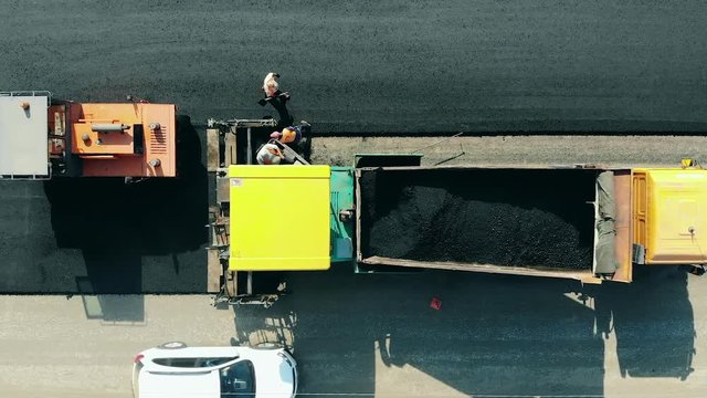 Machines and workers are paving asphalt