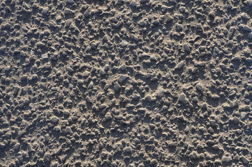 Old worn asphalt with exposed gravel under slant sunlight