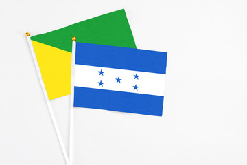 Honduras and French Guiana stick flags on white background. High quality fabric, miniature national flag. Peaceful global concept.White floor for copy space.