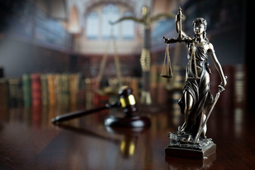Law and justice theme.  Gavel of  the judge, Themis statue and the scale on court library background.