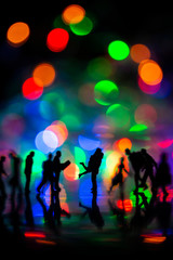 Miniature toy - Silhouette of a couple hugging together among busy commuters crowd with colorful bokeh lights, happiness concept.