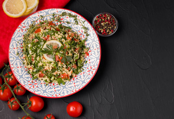 Tabule Salad of bulgur, olive oil, tomato, parsley and spices. on a black background. Eastern cuisine. bulgur dish