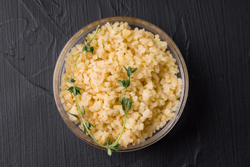 ready-made bulgur porridge with greens on a black background in a transparent bowl