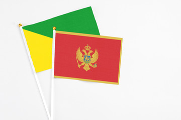 Montenegro and French Guiana stick flags on white background. High quality fabric, miniature national flag. Peaceful global concept.White floor for copy space.