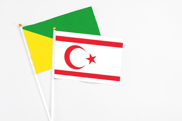 Fototapeta na wymiar Northern Cyprus and French Guiana stick flags on white background. High quality fabric, miniature national flag. Peaceful global concept.White floor for copy space.