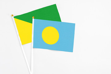 Palau and French Guiana stick flags on white background. High quality fabric, miniature national flag. Peaceful global concept.White floor for copy space.