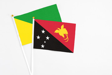 Papua New Guinea and French Guiana stick flags on white background. High quality fabric, miniature national flag. Peaceful global concept.White floor for copy space.