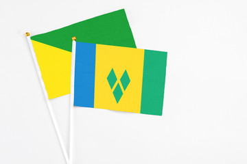 Saint Vincent And The Grenadines and French Guiana stick flags on white background. High quality fabric, miniature national flag. Peaceful global concept.White floor for copy space.