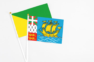Saint Pierre And Miquelon and French Guiana stick flags on white background. High quality fabric, miniature national flag. Peaceful global concept.White floor for copy space.