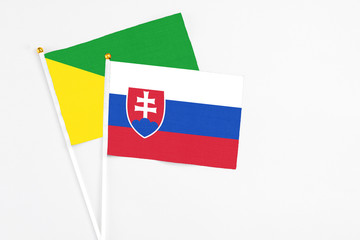 Slovakia and French Guiana stick flags on white background. High quality fabric, miniature national flag. Peaceful global concept.White floor for copy space.