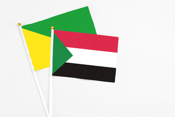 Sudan and French Guiana stick flags on white background. High quality fabric, miniature national flag. Peaceful global concept.White floor for copy space.
