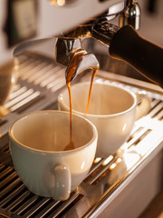 Professional coffee brewing. Close-up of two espresso pouring from coffee machine.