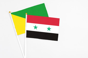Syria and French Guiana stick flags on white background. High quality fabric, miniature national flag. Peaceful global concept.White floor for copy space.