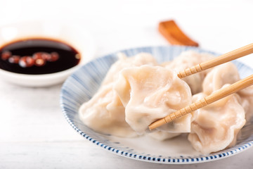 Fresh, delicious boiled pork, shrimp gyoza dumplings on white background with soy sauce and chopsticks, close up, lifestyle. Homemade design concept.