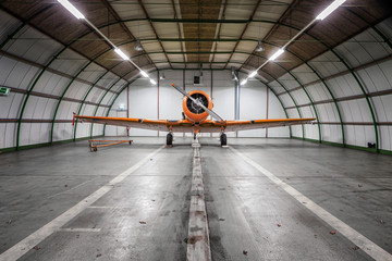 Plane on repair in a big hangar. Single turboprop aircraft in big hangar - obrazy, fototapety, plakaty