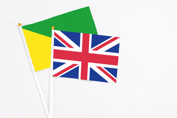 United Kingdom and French Guiana stick flags on white background. High quality fabric, miniature national flag. Peaceful global concept.White floor for copy space.