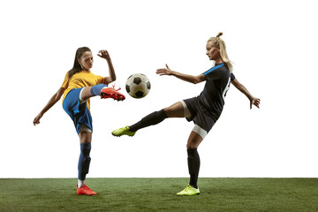 Obraz na płótnie Canvas Young female soccer or football players with long hair in sportwear and boots training on white background. Concept of healthy lifestyle, professional sport, motion, movement. Fight for goal.