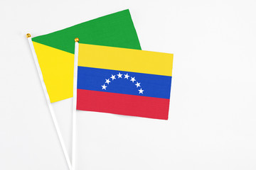 Venezuela and French Guiana stick flags on white background. High quality fabric, miniature national flag. Peaceful global concept.White floor for copy space.
