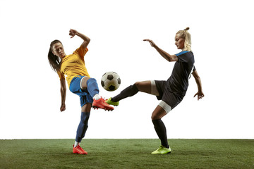 Fototapeta na wymiar Young female soccer or football players with long hair in sportwear and boots training on white background. Concept of healthy lifestyle, professional sport, motion, movement. Fight for goal.