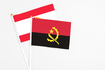 Angola and French Polynesia stick flags on white background. High quality fabric, miniature national flag. Peaceful global concept.White floor for copy space.