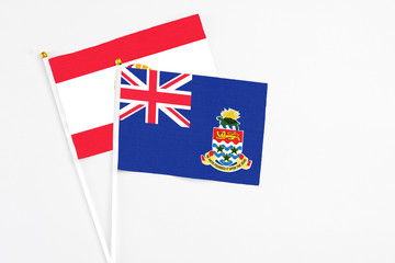 Fototapeta premium Cayman Islands and French Polynesia stick flags on white background. High quality fabric, miniature national flag. Peaceful global concept.White floor for copy space.