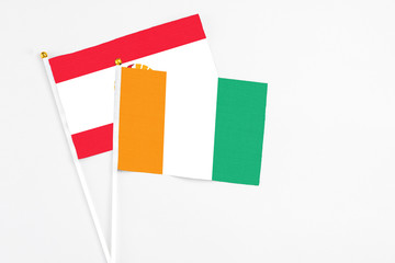 Fototapeta premium Cote D'Ivoire and French Polynesia stick flags on white background. High quality fabric, miniature national flag. Peaceful global concept.White floor for copy space.