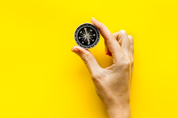 Choose direction concept. Compass in hand on yellow background top view copy space