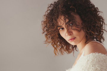 Beautiful woman with curly hair against gray background