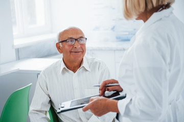 Senior man have consultation in the clinic by the female doctor