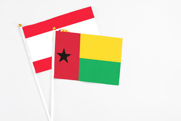 Guinea Bissau and French Polynesia stick flags on white background. High quality fabric, miniature national flag. Peaceful global concept.White floor for copy space.