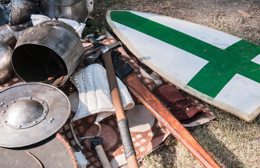 Outfit of a medieval warrior lying picturesquely at a medieval fair. Helmets, shields, chain mail, swords and axes.