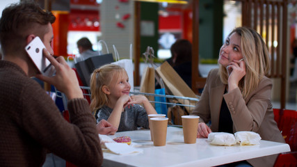 Parents talk on the phone, daughter watches and smile