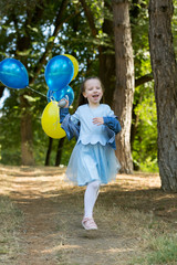 Little cute girl running in the Park with a bunch of balloons. She laughs provocatively. The concept of a happy childhood.