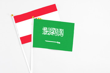 Saudi Arabia and French Polynesia stick flags on white background. High quality fabric, miniature national flag. Peaceful global concept.White floor for copy space.