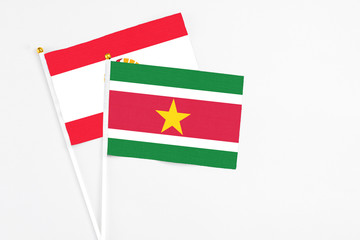 Suriname and French Polynesia stick flags on white background. High quality fabric, miniature national flag. Peaceful global concept.White floor for copy space.