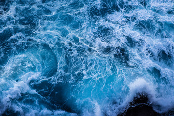 Fototapeta na wymiar Violent energetic waves crashing on a rock in Sydney Australia. Light and dark blue water foaming whilst waves break to the shore. Deep Sea.