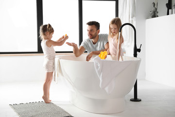 Young father with little daughters in bathroom