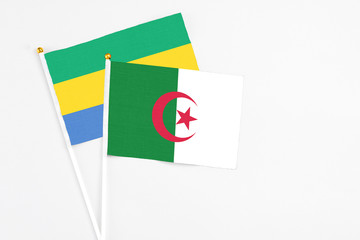 Algeria and Gabon stick flags on white background. High quality fabric, miniature national flag. Peaceful global concept.White floor for copy space.