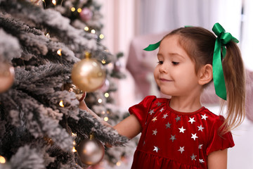 Cute little child near Christmas tree at home