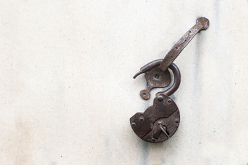 A vintage open wrought iron lock with an inserted key hangs on a vintage beige door handle