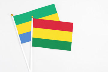 Bolivia and Gabon stick flags on white background. High quality fabric, miniature national flag. Peaceful global concept.White floor for copy space.
