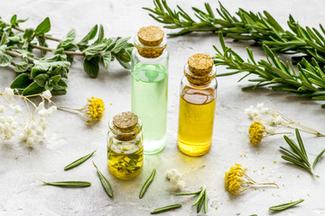Aromatherapy. Essential oils in small bottles near fresh herbs on white background