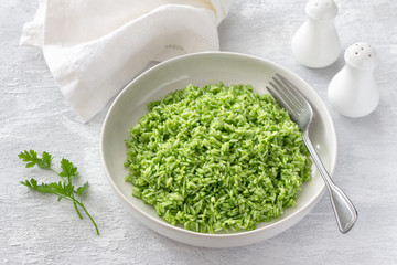 Vegan rice with green oil in a white bowl on a gray background. delicious healthy homemade food	