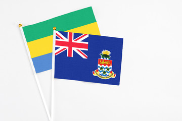 Cayman Islands and Gabon stick flags on white background. High quality fabric, miniature national...