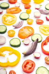Bright colorful vegetables background. Salad ingredients, tomatoes cucumber peppers onions cut on white, side view, selective focus